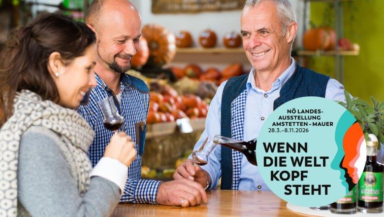 Wurzers, © Daniel Schalhas Drei Personen verkosten Wein in einem Marktstand mit Kürbissen im Hintergrund.