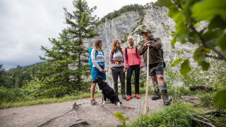 Gruppe von Wanderern mit Hund in bergiger Landschaft.