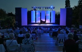 Open-Air-Konzert bei Nacht mit Publikum und beleuchteter Bühne.
