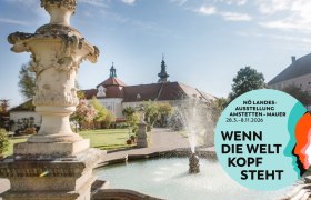 Garten mit Brunnen und Klostergebäude im Hintergrund, Plakat für NÖ Landesausstellung 2026.