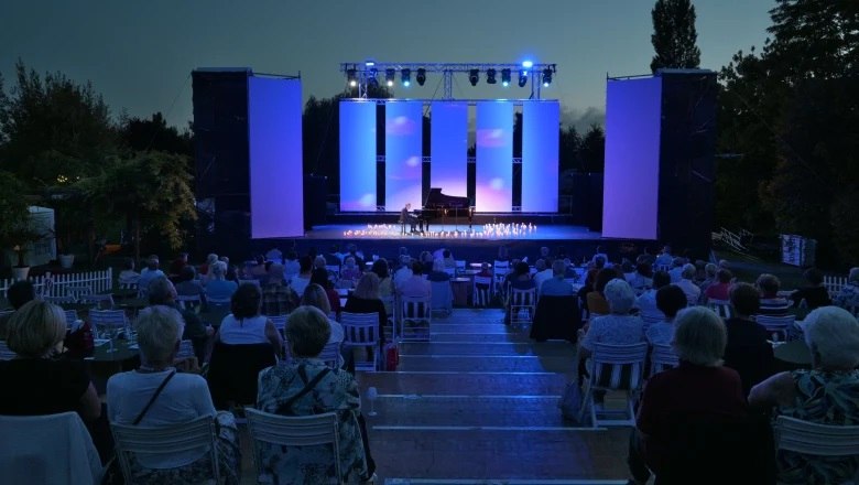 Open-Air-Konzert bei Nacht mit Publikum und beleuchteter B&uuml;hne.