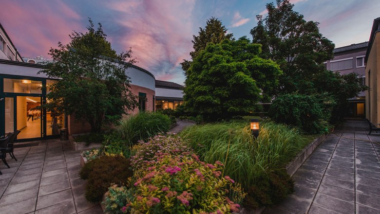 Innenhof des Bildungshauses St. Hippolyt mit Garten und Abendhimmel.
