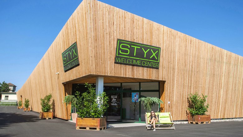 Modernes Geb&auml;ude mit Holzverkleidung und STYX Welcome Center Schild.