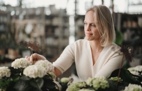 Eine Frau pflegt Blumen in einem Gewächshaus.