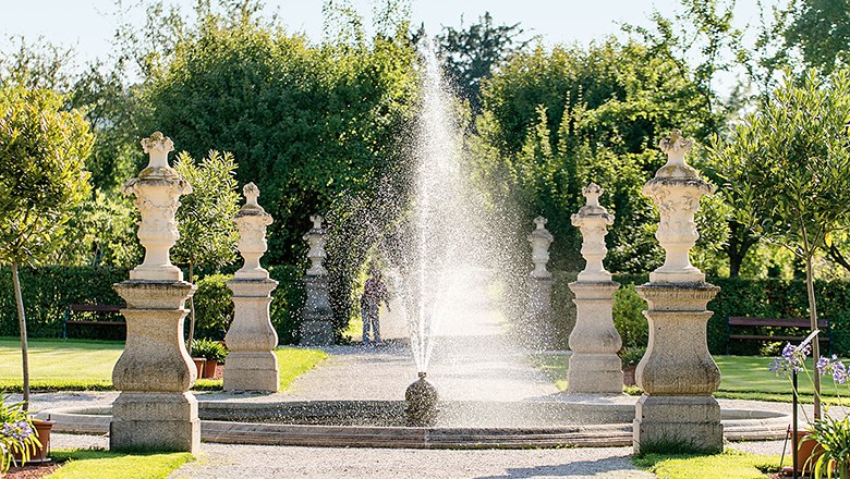 Springbrunnen im Garten des Stifts Seitenstetten mit Statuen und B&auml;umen im Hintergrund.